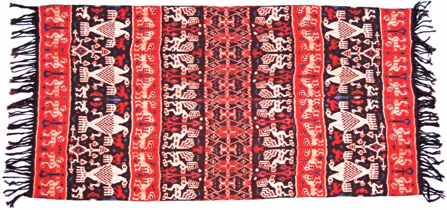 Photographie illustrant un tapis décoratif arborant un motif lions coqs et oiseaux issu du tissage Ikat