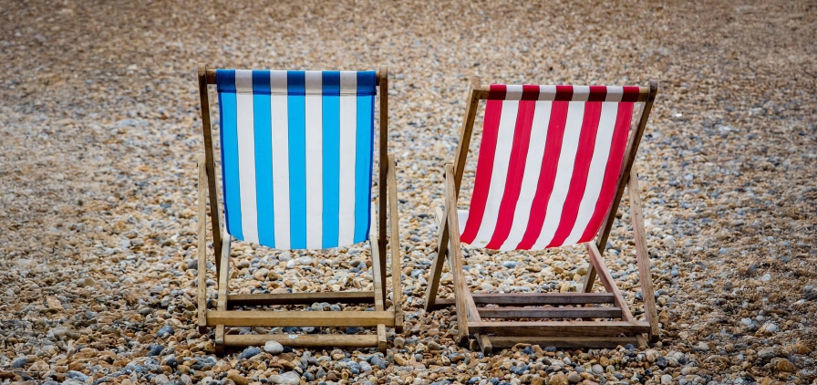 Photo de chaises longues à motif rayures sur une plage de galet